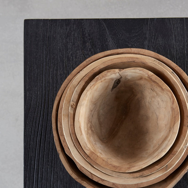 stack of wooden bowls nested within each other on a blackened bench which itself is stood on a concrete floor