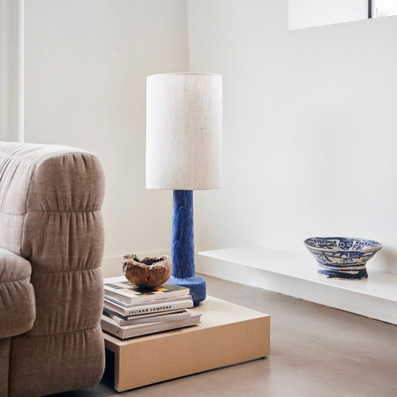 hkliving lamp in blue with a boucle white lamp shade next to a plush sofa