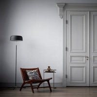 the chair in a large room with a lamp and over sized double door, closed to the outside