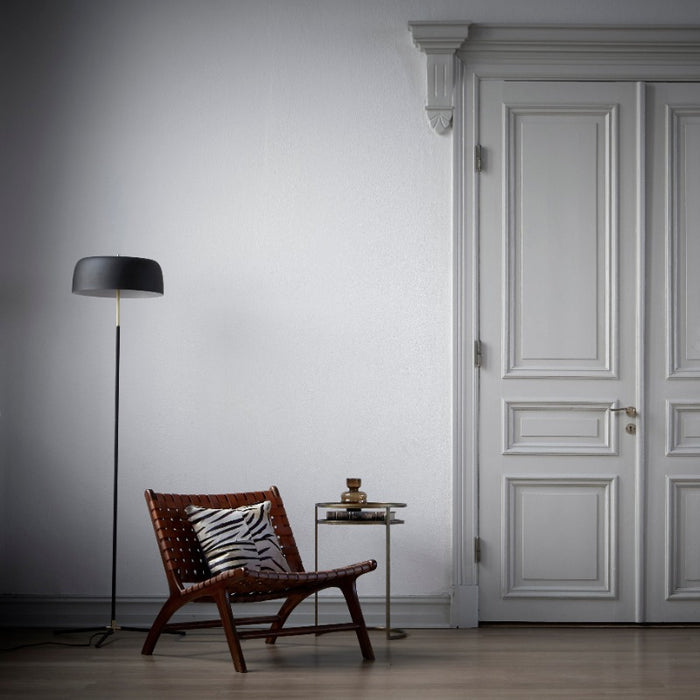 the chair in a large room with a lamp and over sized double door, closed to the outside