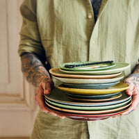stack of multicoloured plates from hklivings 70s collection held by someone at north home in leeds