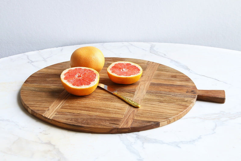 thedifferent colours of this teak wood circular choppping board lend it an age that it wouldn't normally have and with a small hkliving logo next to the fish tail handle