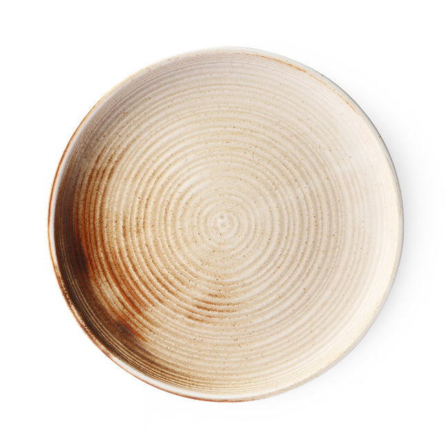 a hand painted plate in beige with a patch of dark brown coming in form the side of this hkliving plate