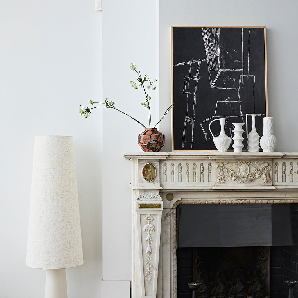 set of 4 white vavses stood on a mantlepiece with other hkliving vases and lamps